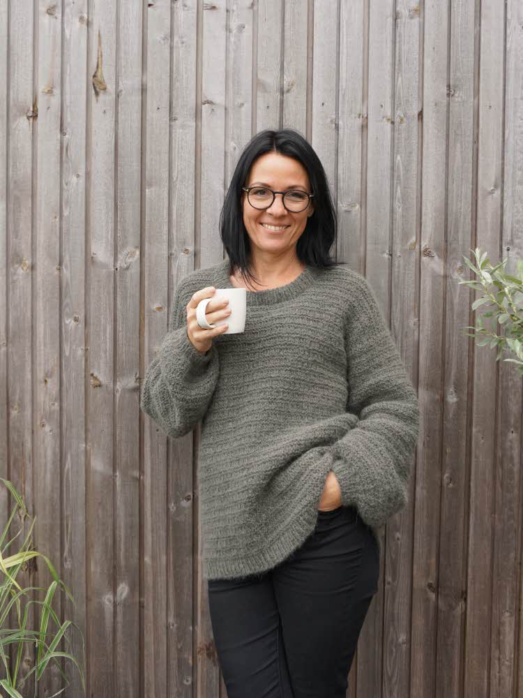 Dame i strikkegenser holder en kaffekopp