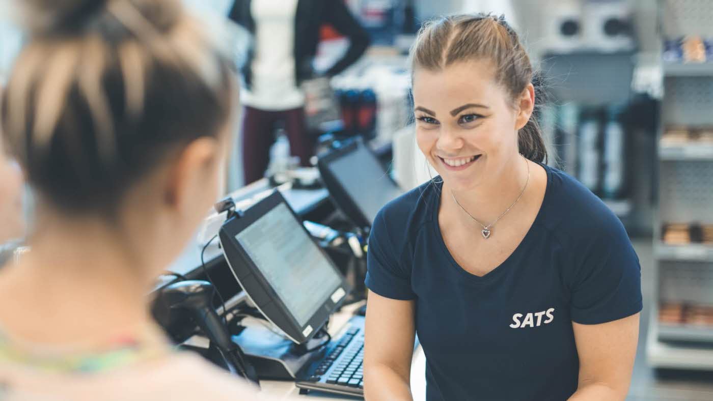 Trener på Sats blid og smilende på treningssenter