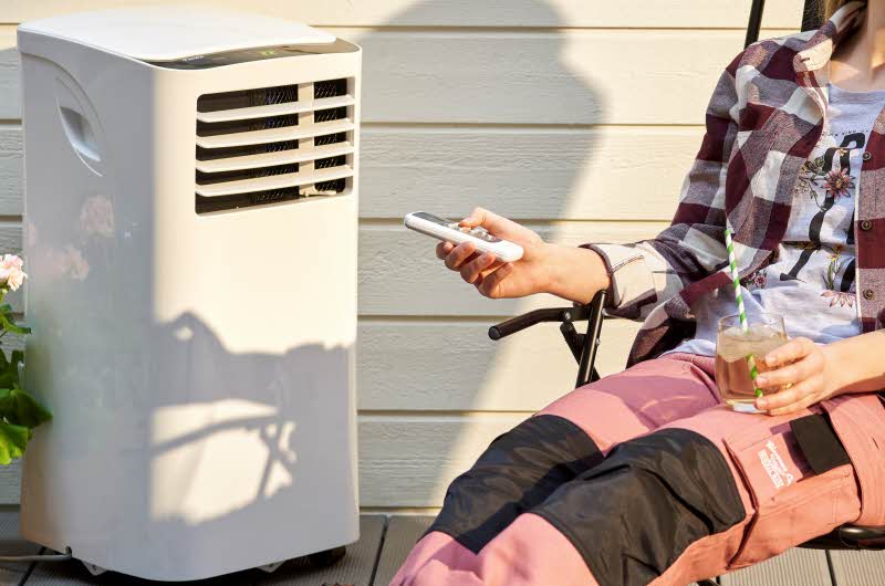 dame som sitter ute foran ett hvitt klimaanlegg