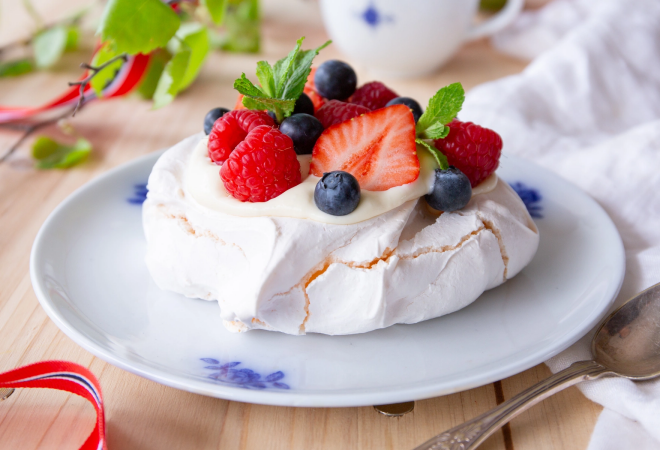 En asjett med pavlova kake med krem, blåbær og jordbær