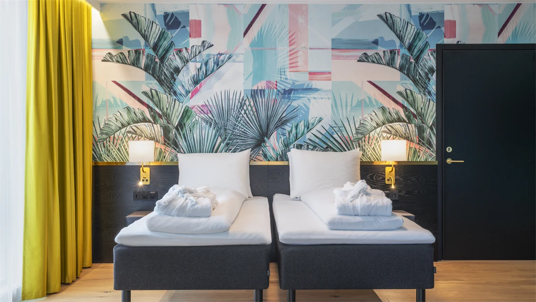 Separate senger og fargerik palmetapet i standard twin rom på Thon Hotel Storo