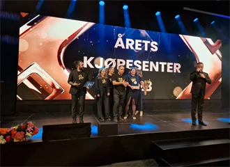 Ansatte på Kvadrat står samlet på stor scene etter å ha vunnet prisen, foran skjerm der det står årets kjøpesenter.