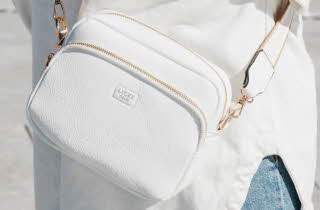Hvit crossbody-veske med gullglidelåser fra LYCKE Oslo.