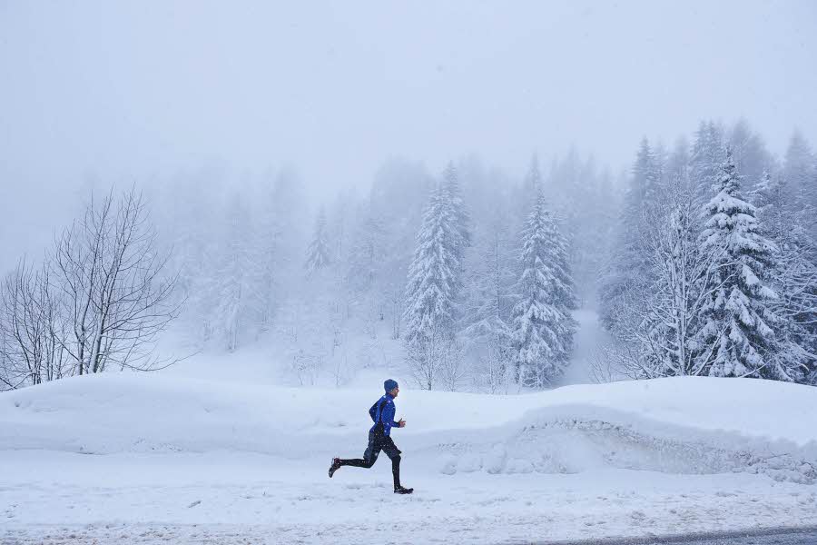 Mann i vinterlandskap som løper, sett i profil fra avstand