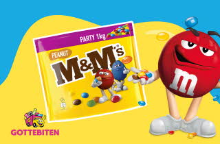 En pose med M&M's og en stor M&M med armer, bein og ansikt som står ved siden av