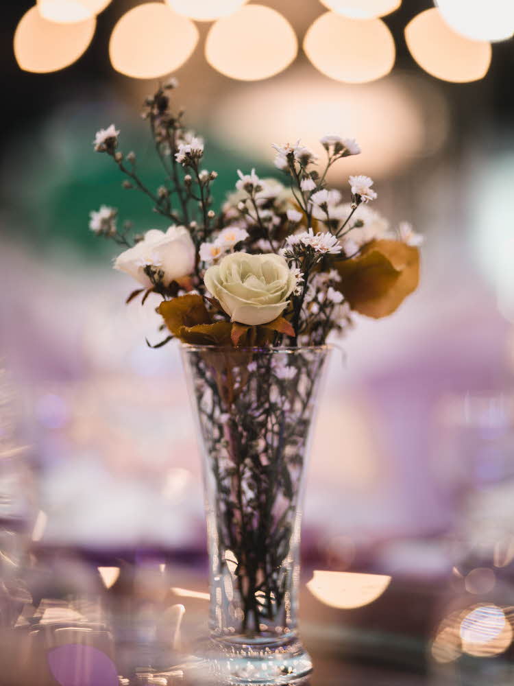 Blomsterbukett i vase med lys i bakgrunnen