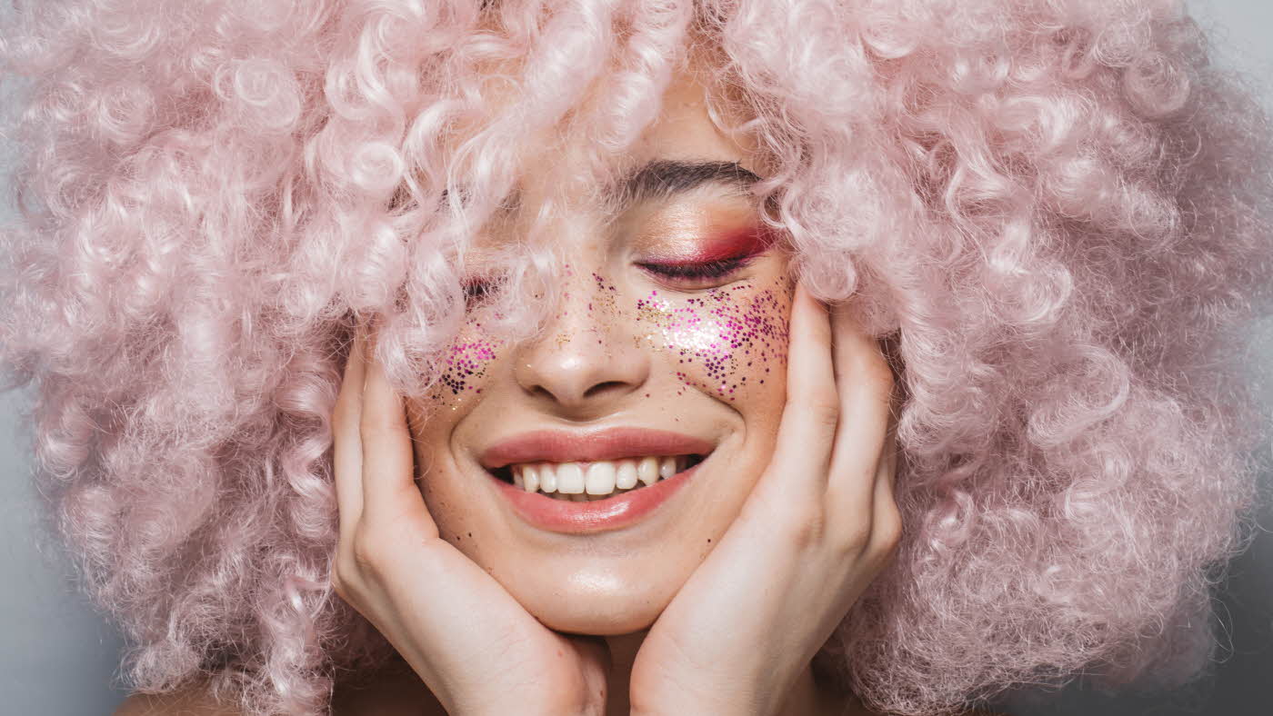 Nærbilde av kvinne med rosa hår og glittersminke