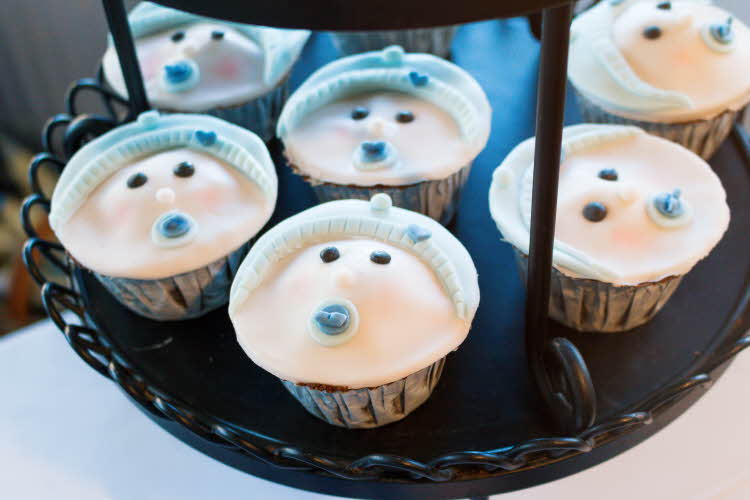 Muffinser dekorert med babyfjes med blå smokker. Illustrasjonsfoto til artikkel om kaker til babyshower.