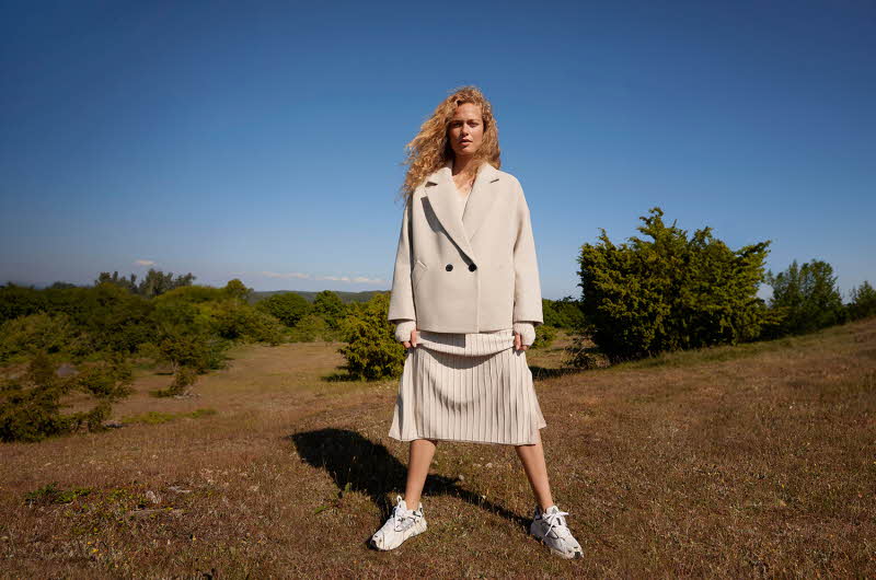 Dame poserer med beige dressjakke og beige skjørt