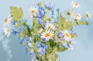 Bukett med hvite og blå blomster i en glassvase.