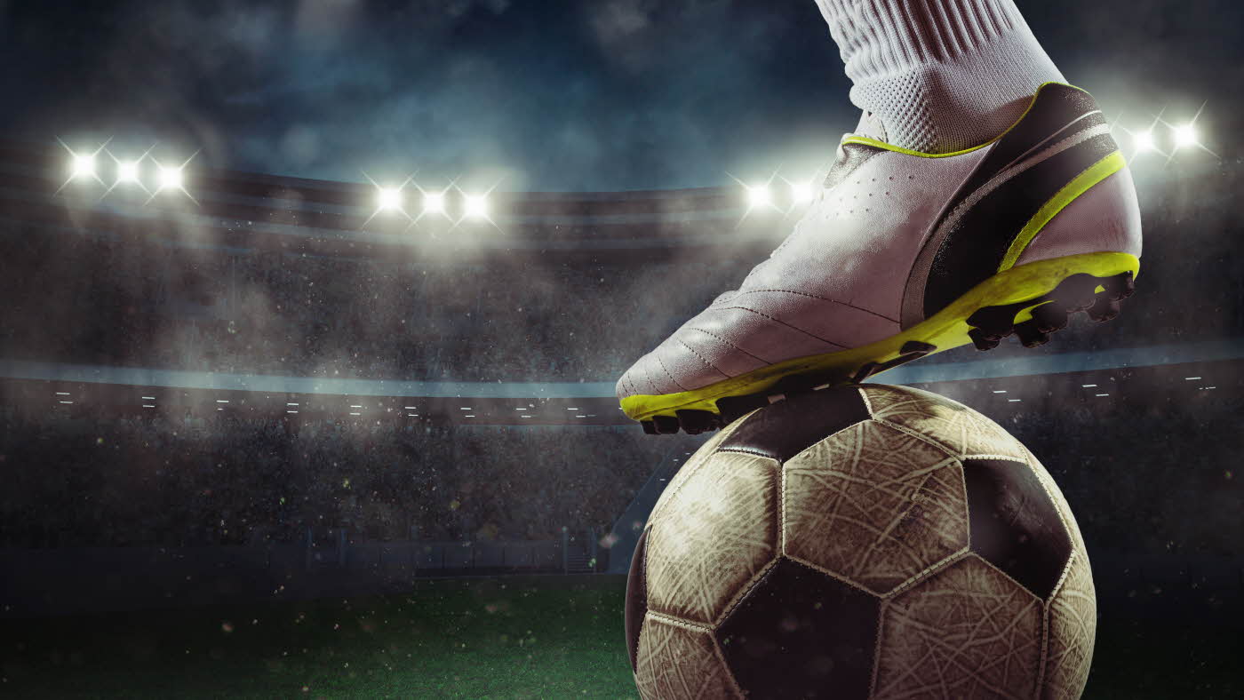 Fotballsko oppå en fotball på en stadion