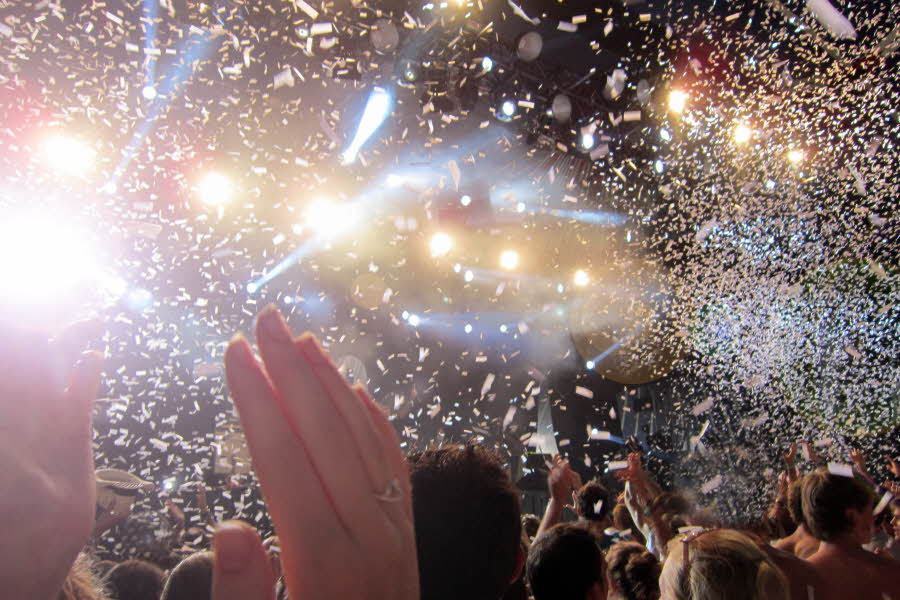 Konfetti i lufta på en konsert på festival med hender i lufta