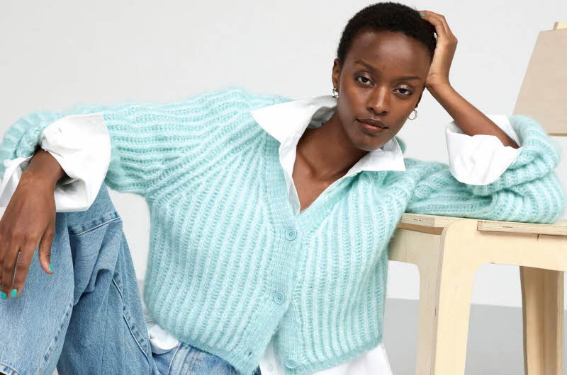dame som poserer i hvit skjorte, blå strikket genser og blå jeans