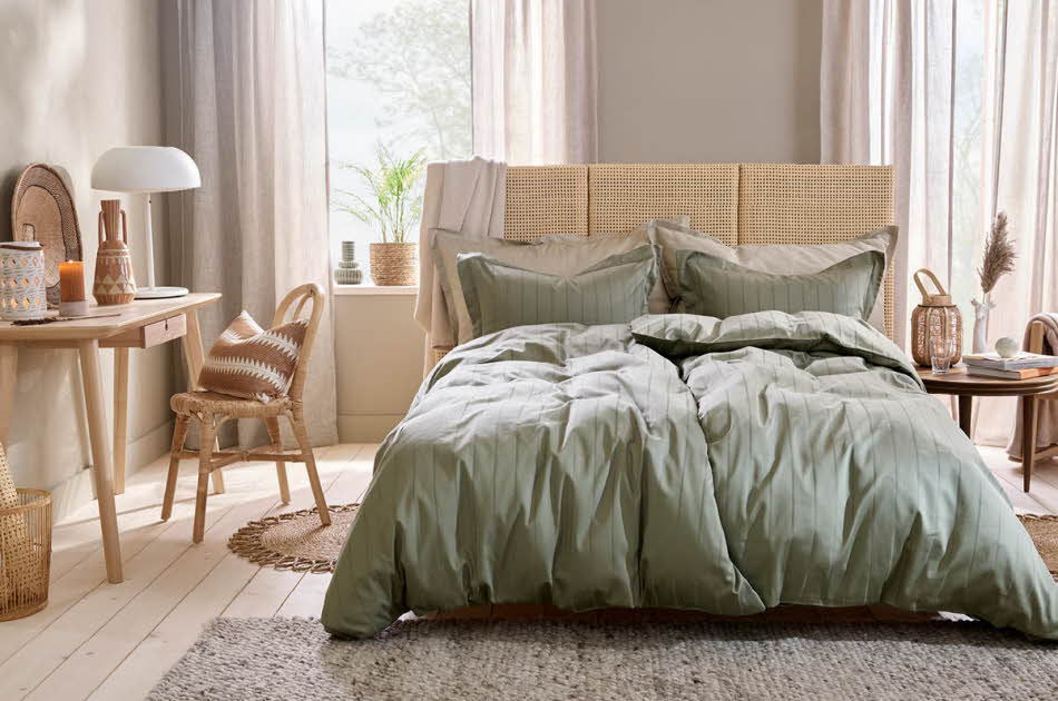 miljøbilde av seng med grønt sengetøy