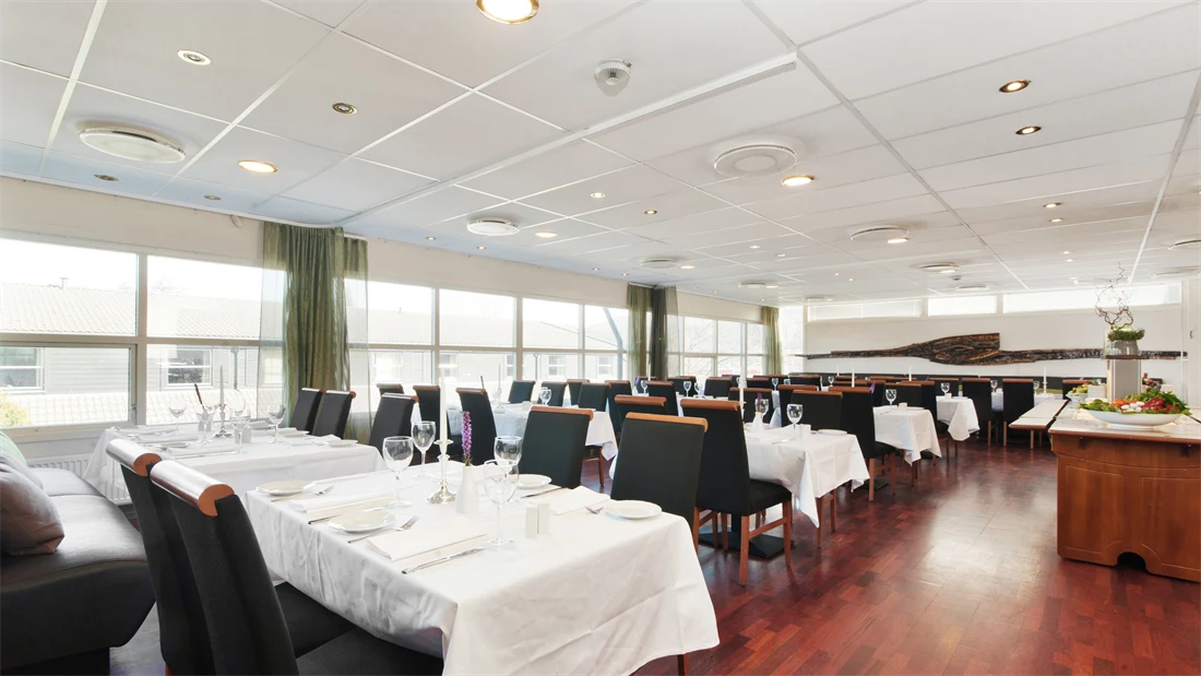 Restaurant med lange bord med hvite duker og sorte stoler i restauranten til Thon Hotel Sandnes