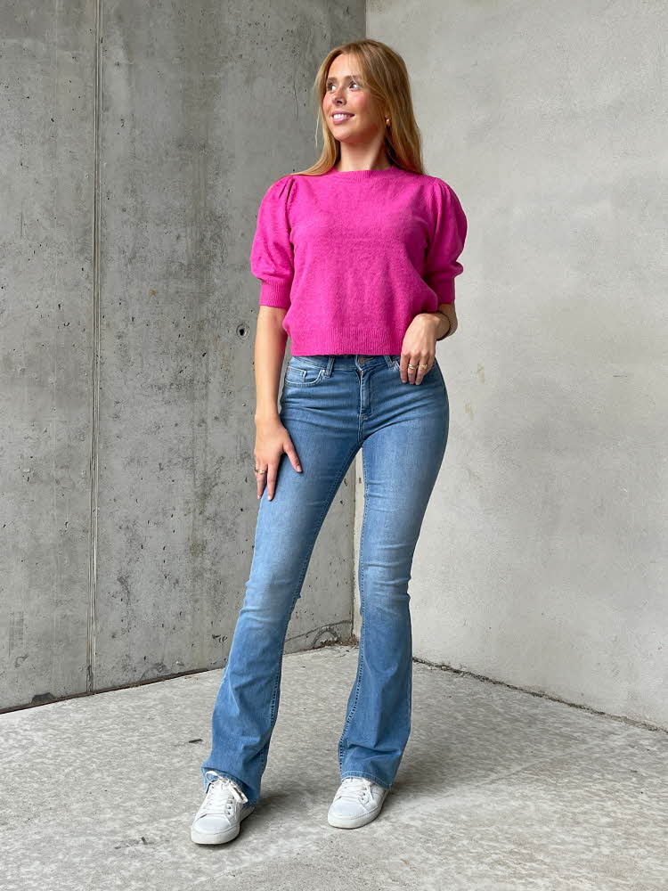Ung jente med rosa topp, jeans og hvite sneakers.