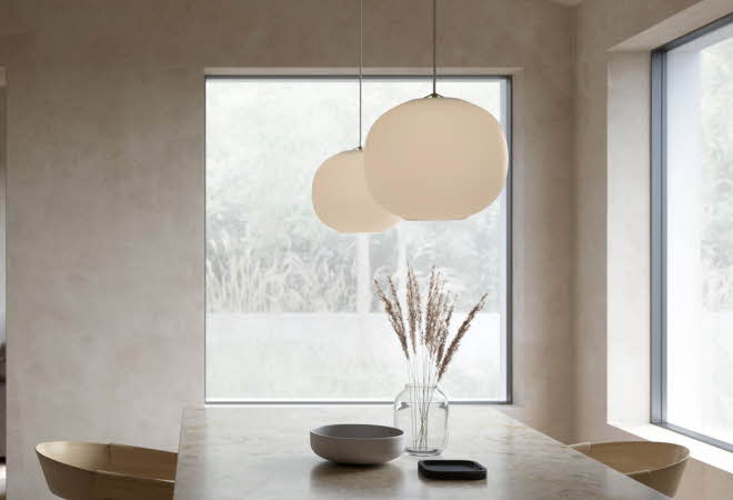 Spisestue med to store pendellamper over marmorbord.