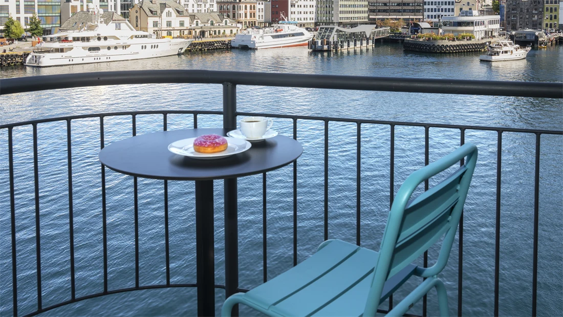 Balkong med utsikt over vannet og blå himmel, stoler, bord 