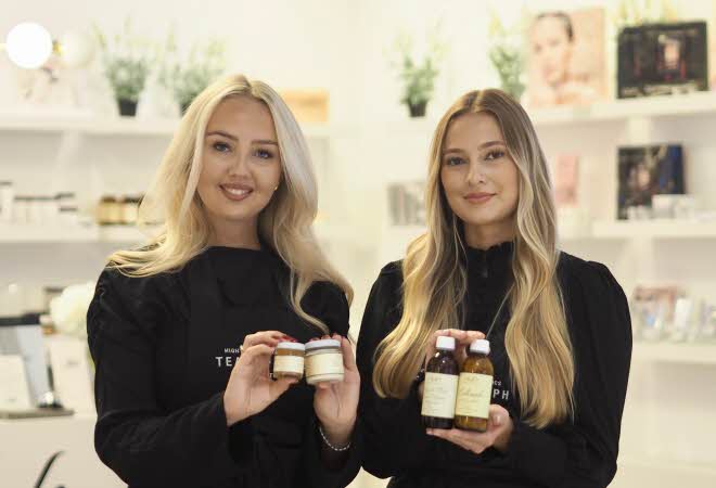 To ansatte viser frem produkter fra Auds Hudpleie