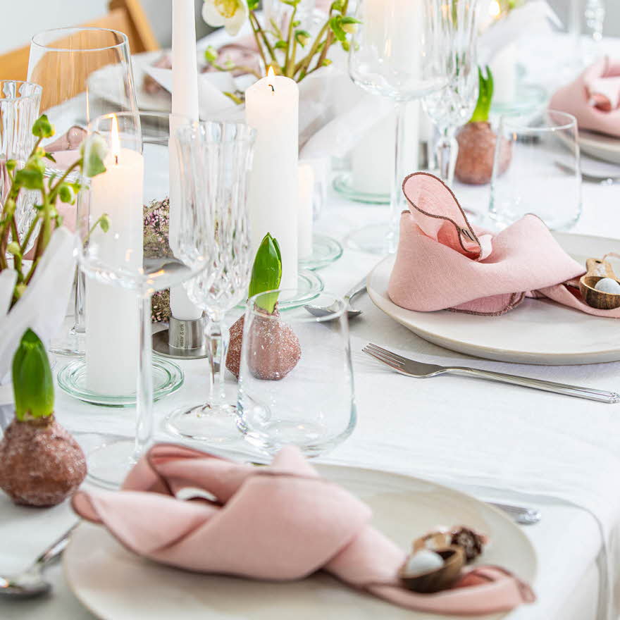 Langbord dekker til gjester med rosa servietter og grønn naturlig dekorasjon