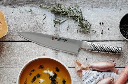 kniv på kjøkkenbenk ved siden av suppe og urter