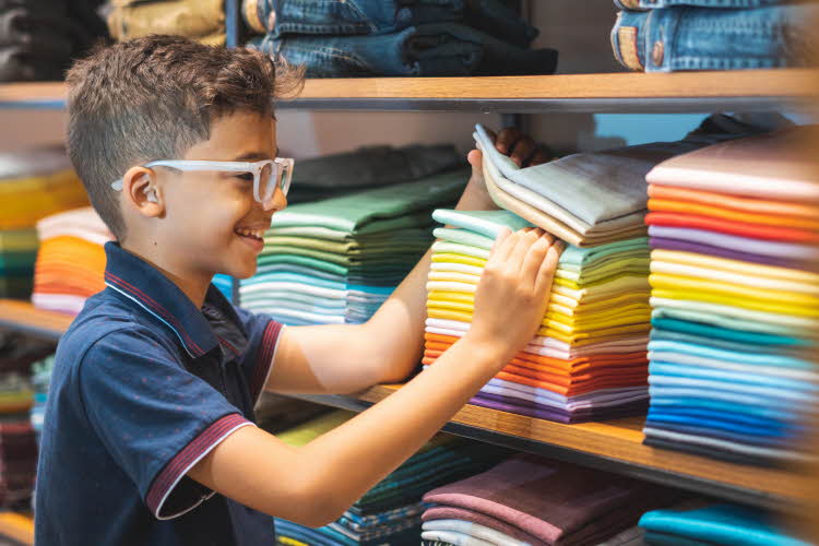 gutt med stilige briller som ser på  klær i klesbutikk