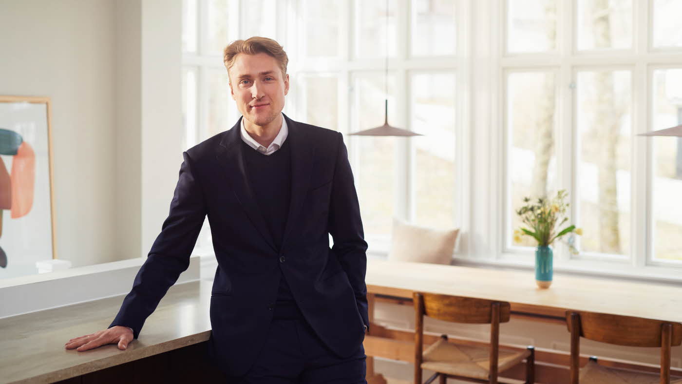 En mann som står og lener seg mot en benk i en leilighet