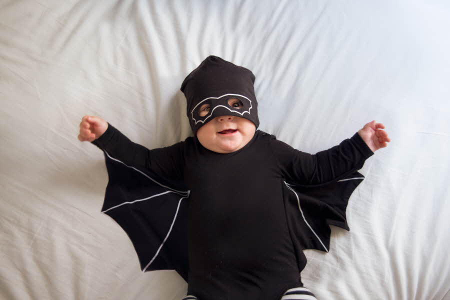 Baby som ligger i et svart flaggermus kostyme