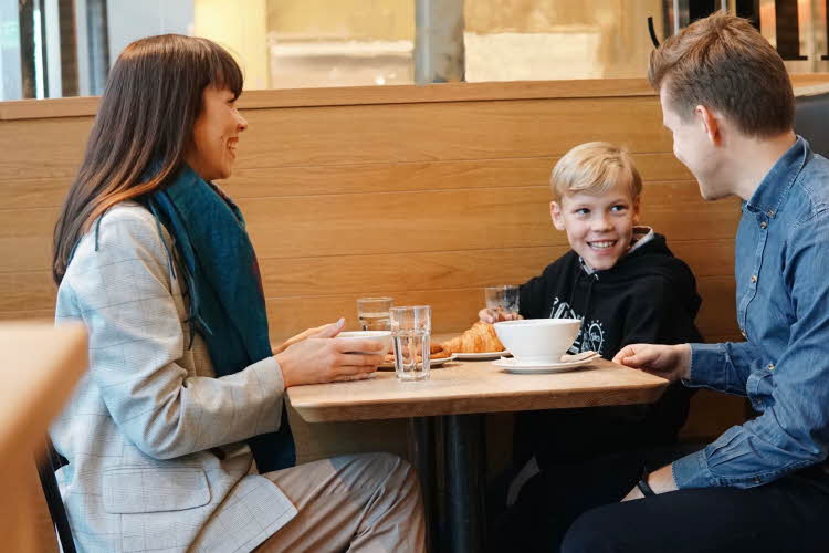 Dame, mann og en gutt som spiser og smiler