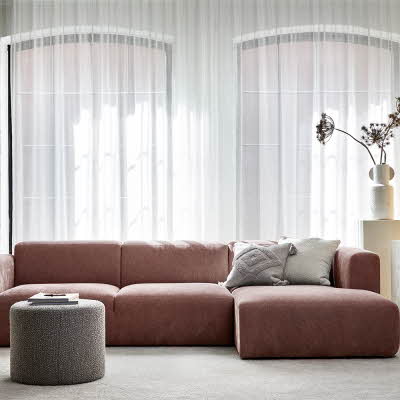 Stue med store vinduer og en rødlig sofa