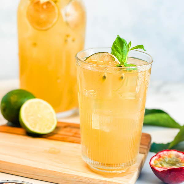 et glass med lemonade, dekorert med frukt rundt på bordet og en glassflaske med lemonade i bakgrunnen