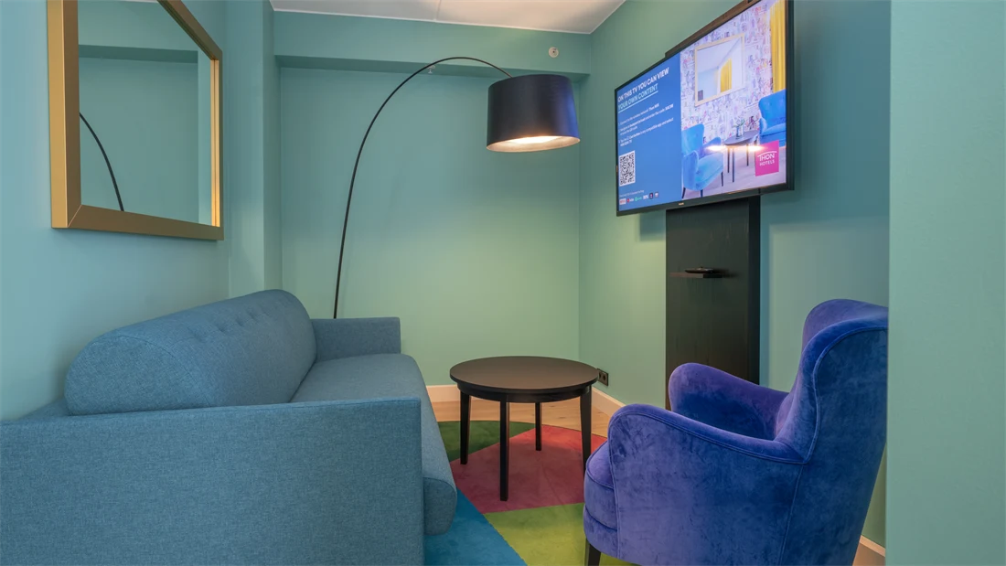 Sittegruppe med turkis sofa og blå stol og smart TV i business rom på Thon Hotel Storo