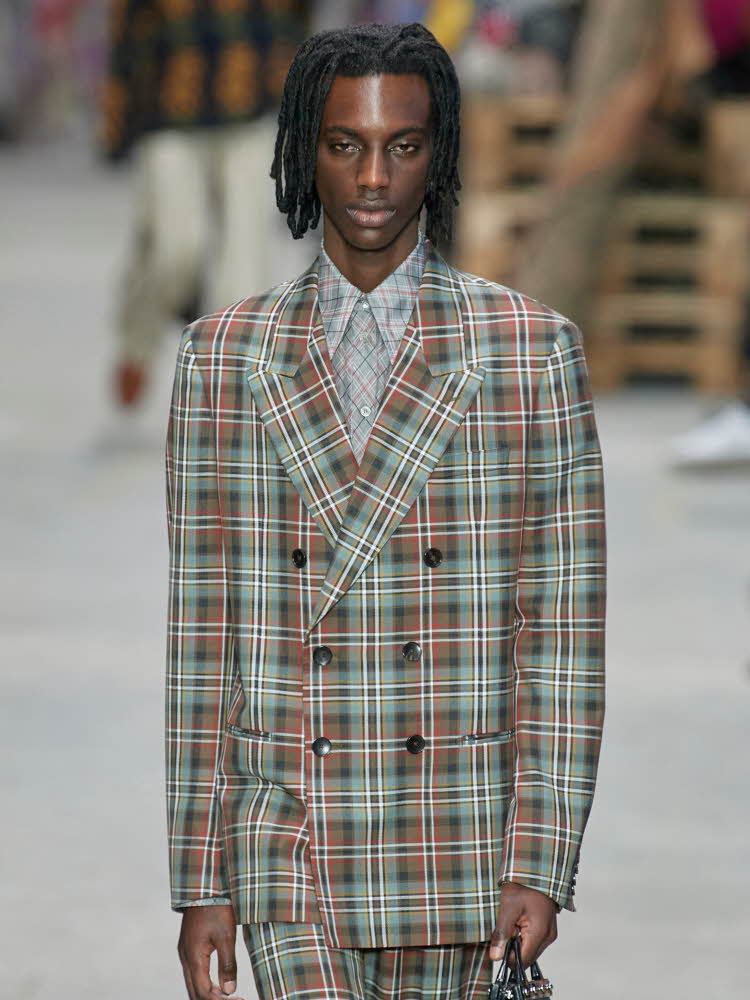 Herremodell på catwalk med rutete dress og mønstret skjorte.