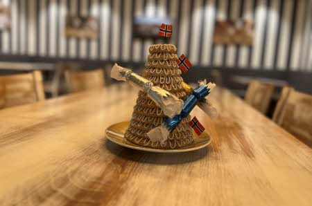 En pyntet kransekake står på et langbord med blurry bakgrunn