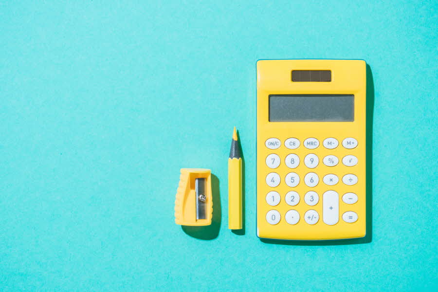 Flat lay av kalkulator, penn og blyantspisser i gult