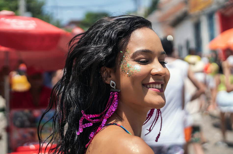 En kvinne med glitrende sminke på kinnene som går nedover gaten. Foto til artikkel om festivalsminke.