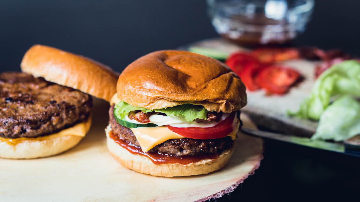 Hamburger med ingredienser i bakgrunnen