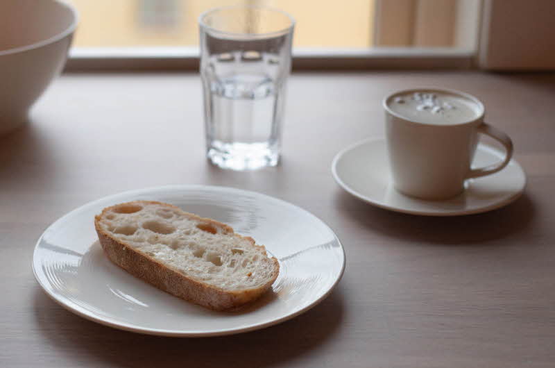 spisebord med tallerken med brød, kopp med kaffe og et glass