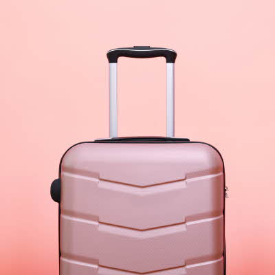 Rosa koffert foran rosa bakgrunn