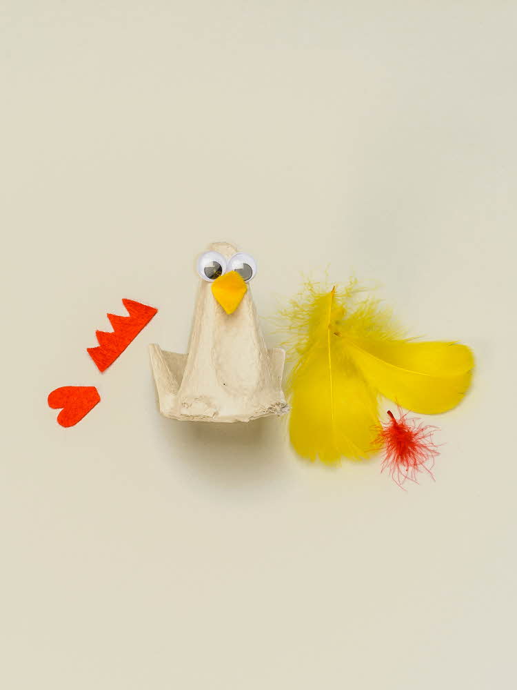 En eggekartong omgjort til en høne med øyne og nebb, resten av utstyret ligger ved siden av