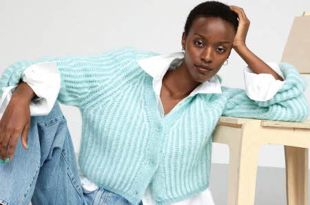 dame som poserer i hvit skjorte, blå strikket genser og blå jeans