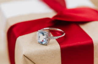 En Jacqueline diamantring som ligger oppe på en innpakket gave.