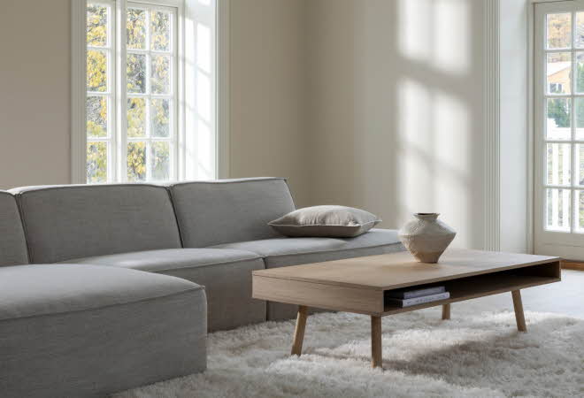En stue med en stor grå sofa og et stuebord