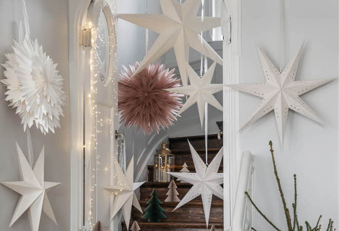 Hvite og rosa papirstjerner henger i en trappoppgang.