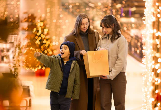 Gutt peker begeistert på noe han ser og damer som ser i shoppingpose