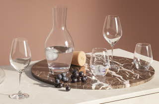 Forskjellige glass og en karaffel fra Holmegaard som står på en plate.