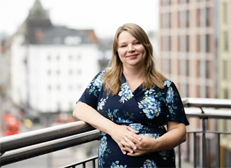 Portrett av Anna Marie Fjeld. Hun står foran et gjerde. 