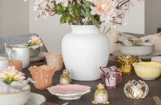 Et bord med mange telyseholdere og en vase med blomster