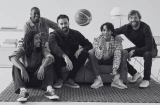 Svart-hvitt bilde av fem menn som sitter i en sofa med en basketball.