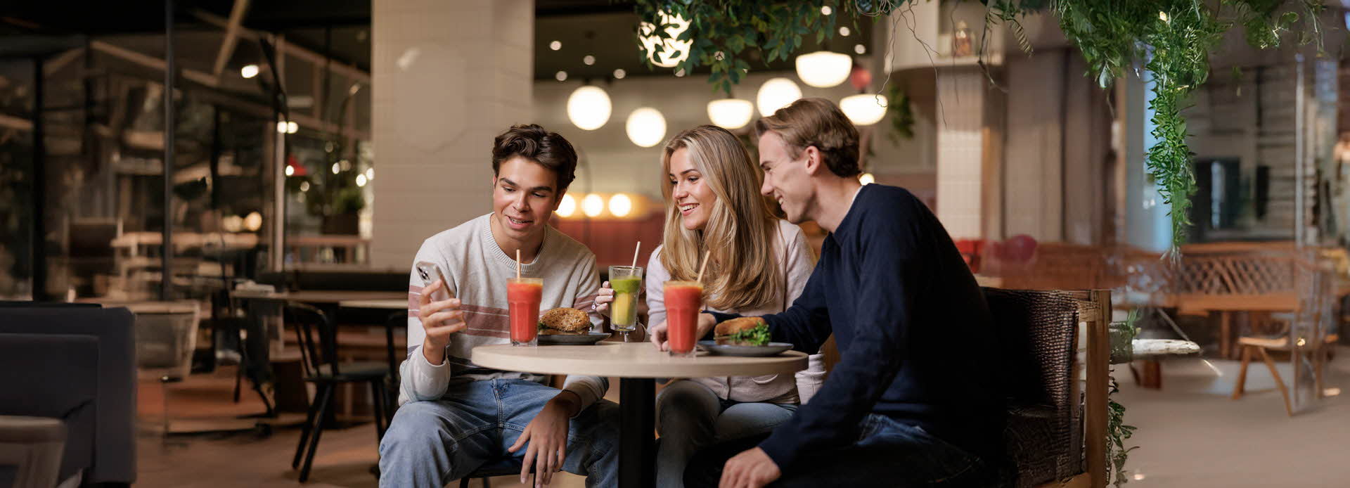 Tre ungdommer som sitter på kafe